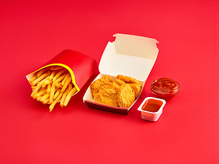 Image showing chicken nuggets and french fries on red background