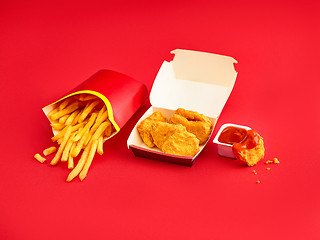 Image showing chicken nuggets and french fries on red background