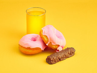 Image showing The donuts and fresh orange juice on yellow background