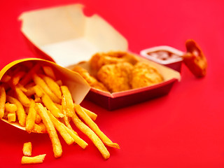 Image showing chicken nuggets and french fries on red background