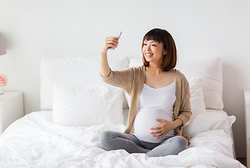 Image showing pregnant woman taking selfie by smartphone at home