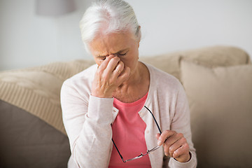 Image showing senior woman with glasses having headache at home