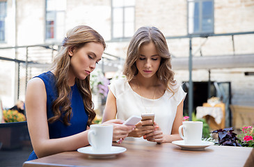 Image showing young women with smartphones and coffee at cafe