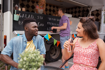 Image showing friends with drinks sitting at table at food truck