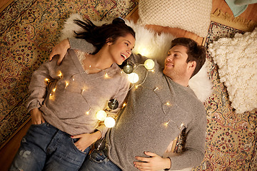 Image showing happy couple with garland lying on floor at home