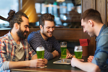 Image showing friends with tablet pc and green beer at pub