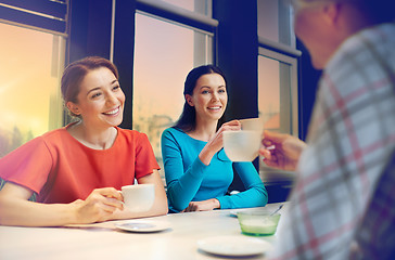 Image showing happy young women drinking tea or coffee at cafe