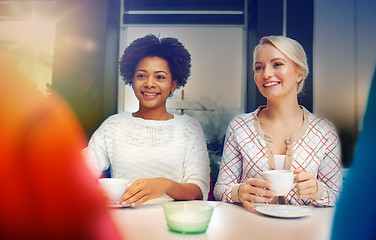 Image showing happy young women drinking tea or coffee at cafe