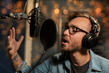 Image showing man with headphones singing at recording studio