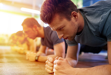 Image showing man doing plank exercise at group training in gym