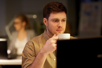 Image showing man with laptop and coffee working at night office