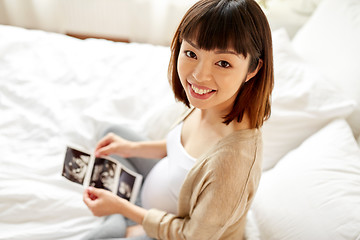 Image showing pregnant woman with fetal ultrasound image at home