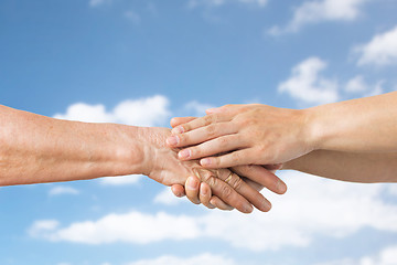 Image showing close up of senior and young woman holding hands