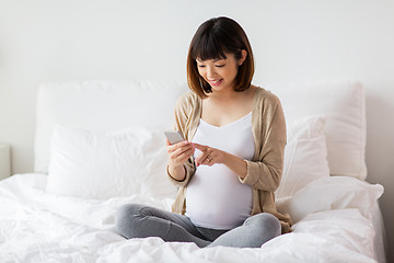 Image showing pregnant woman with smartphone in bed at home