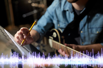 Image showing musician with guitar and music book at studio