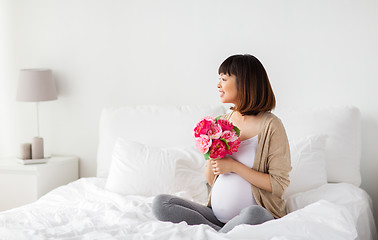 Image showing happy asian pregnant woman with flowers in bed