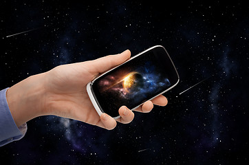 Image showing hand with planet on smartphone screen over space