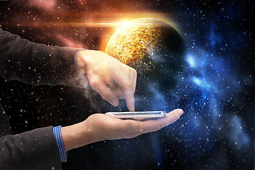 Image showing hands holding smartphone over planet in space