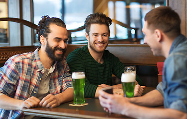 Image showing friends with smartphone drinking green beer at pub