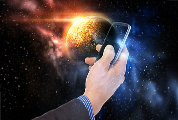 Image showing hand holding smartphone over planet in space