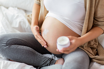 Image showing close up of pregnant woman applying cream to belly