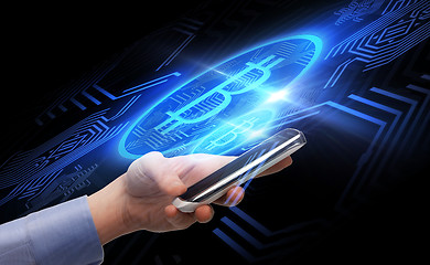 Image showing close up of hand with smartphone and bitcoin