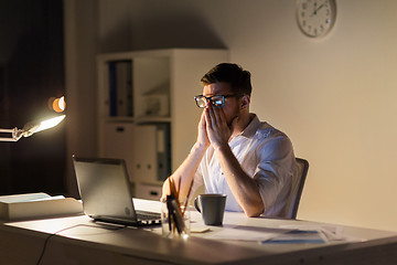 Image showing tired businessman with laptop at night office