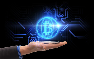 Image showing close up of hand with smartphone and bitcoin