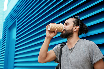 Image showing man drinking coffee from paper cup over wall