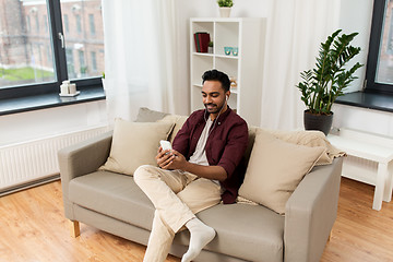 Image showing man in earphones listening to music on smartphone