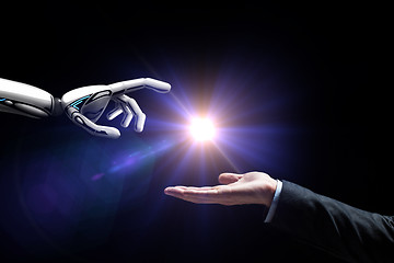 Image showing robot and human hand flash light over black