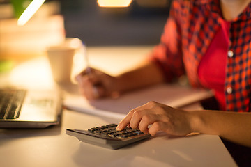 Image showing female student hand counting by calculator at home