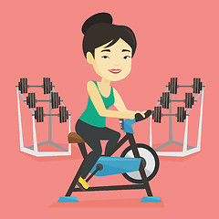 Image showing Young woman riding stationary bicycle.