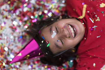 Image showing kid blowing confetti while lying on the floor