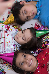 Image showing kids  blowing confetti while lying on the floor