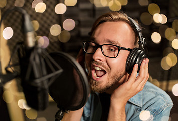 Image showing man with headphones singing at recording studio