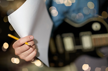 Image showing man with guitar, pencil and paper at music studio