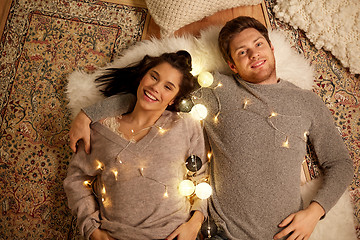 Image showing happy couple with garland lying on floor at home