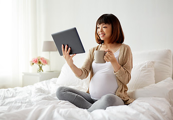 Image showing happy pregnant asian woman with tablet pc at home
