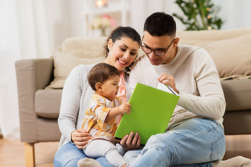 Image showing happy family with baby reading book at home