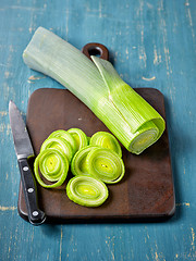 Image showing fresh green leek on wooden cutting board