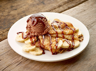 Image showing Crepes with banana and chocolat icecream on wooden desk