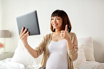 Image showing happy pregnant asian woman with tablet pc at home