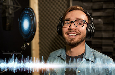 Image showing man with headphones singing at recording studio