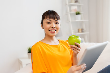 Image showing happy asian woman with tablet pc and apple at home