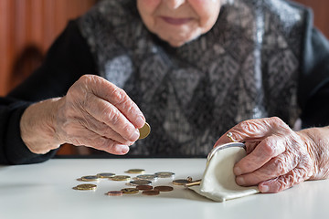 Image showing Elderly woman sitting at the table counting money in her wallet.