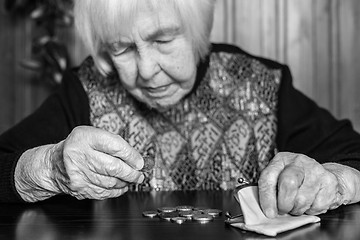 Image showing Elderly woman sitting at the table counting money in her wallet.