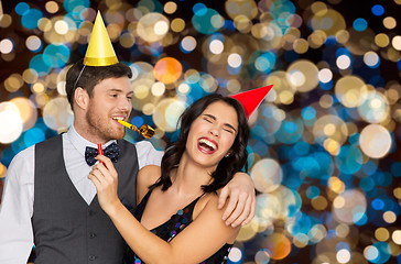 Image showing happy couple with party blowers having fun