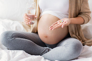 Image showing close up of pregnant woman with pills in bed