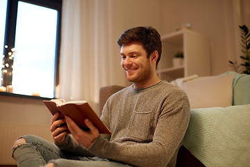 Image showing happy young man reading book at home